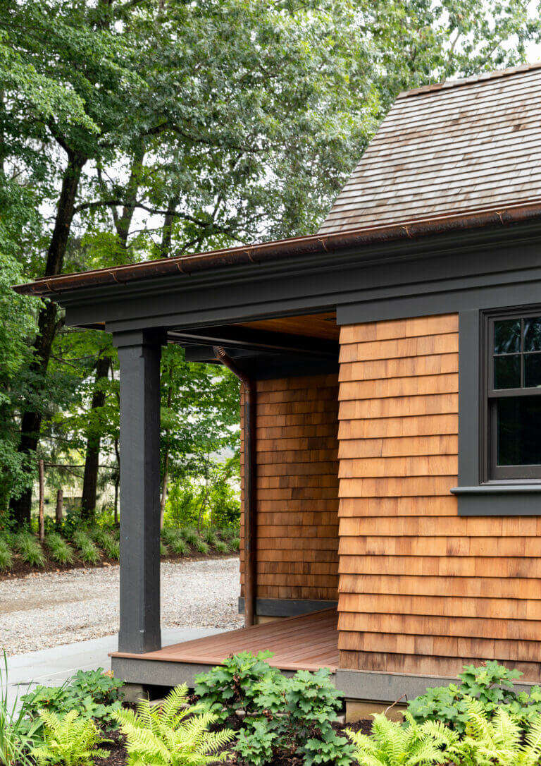 Side Porch View of a cedar shingle and dark green trim custom barn designed residential home