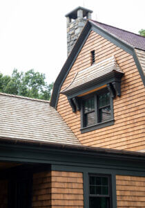 Dutch Barn Roof line with stone chimney and Dark Green Trim