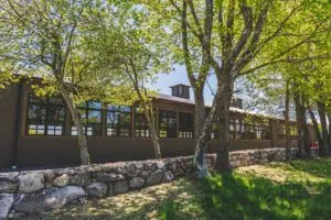 A stone wall in the foreground with a custom designed and built indoor riding arena behind