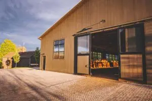 Doors open to an indoor riding area with horse stables behind