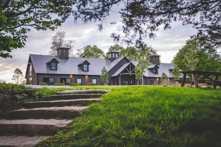 A horse barn with a picnic table out front under the trees